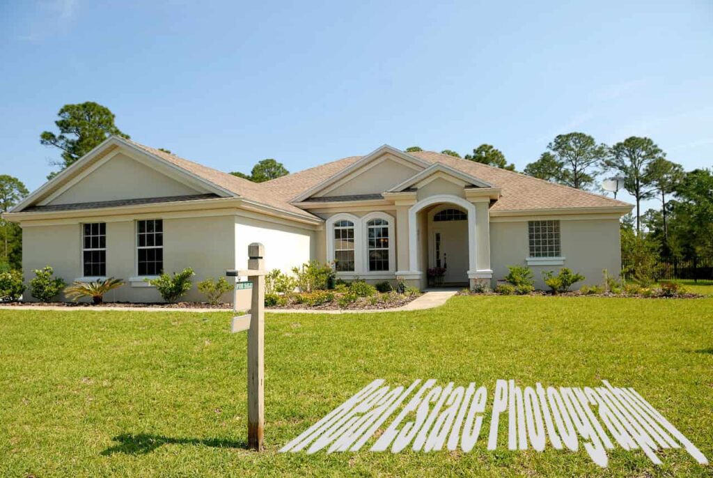 A white and brown concrete bungalow with a big front yard under a clear blue sky