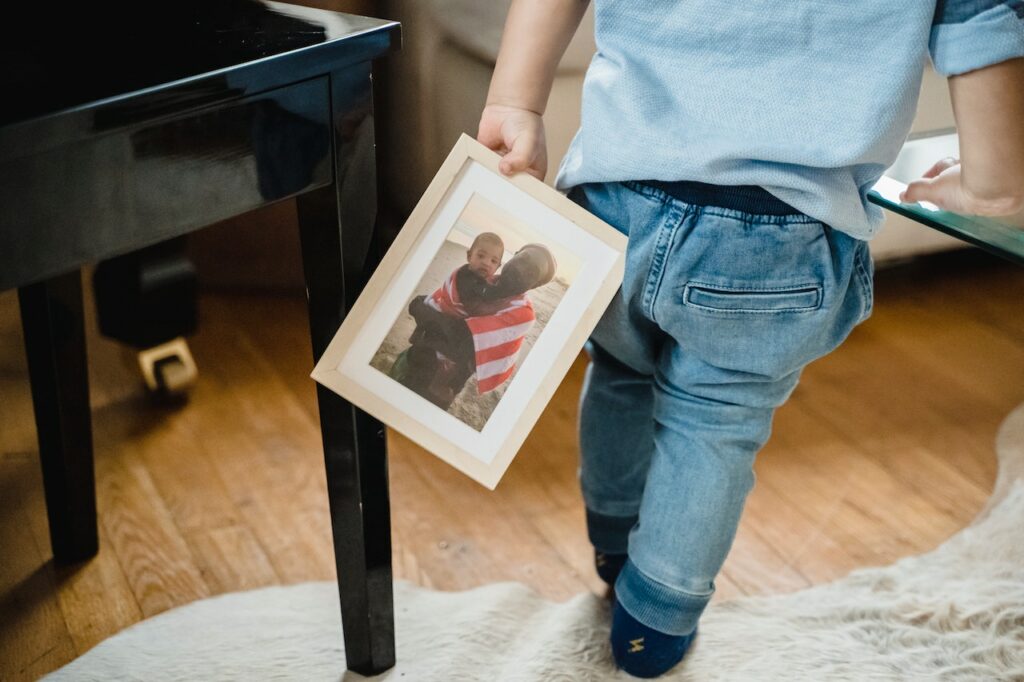 A child holding a wooden picture frame with an image of a son and father on it