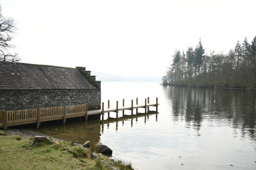 A stone house with a brown wooden bridge near a large lake