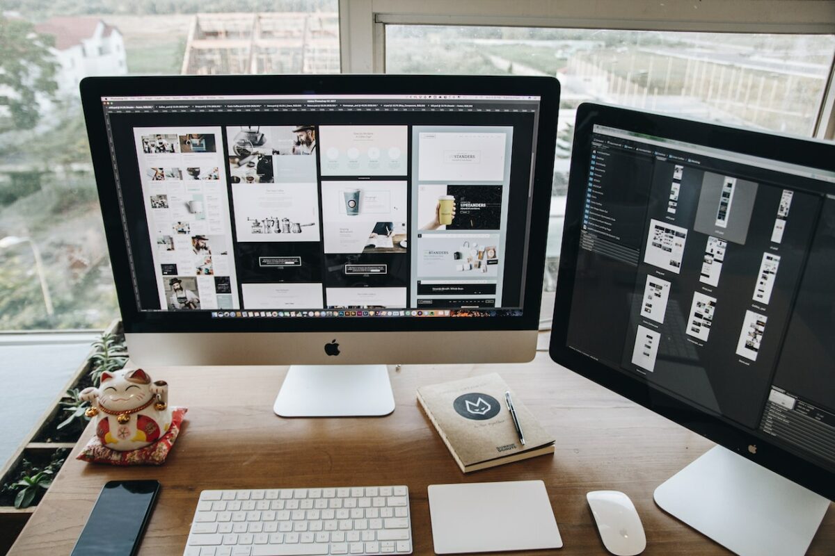 A silver iMac near a black, white keyboard, and a white mouse on top of a brown wooden table