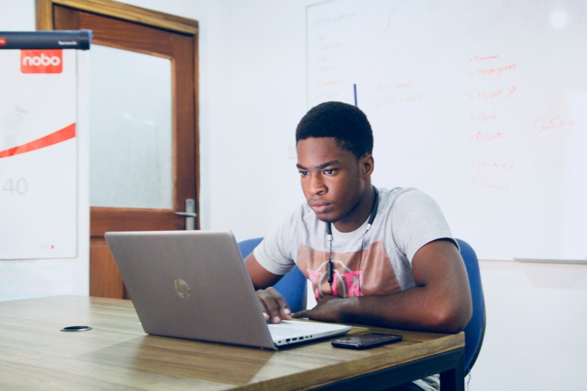 A man wearing a t-shirt uses a silver laptop in the discussion room