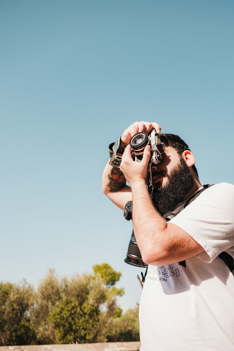 Ein Mann in einem T-Shirt fotografiert mit einer DSLR-Kamera den Himmel