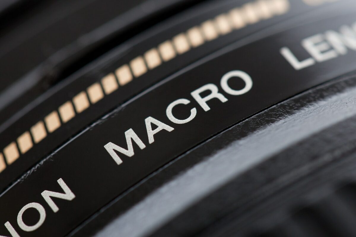 A black macro lens with white engravings with hairline scratches and little dents