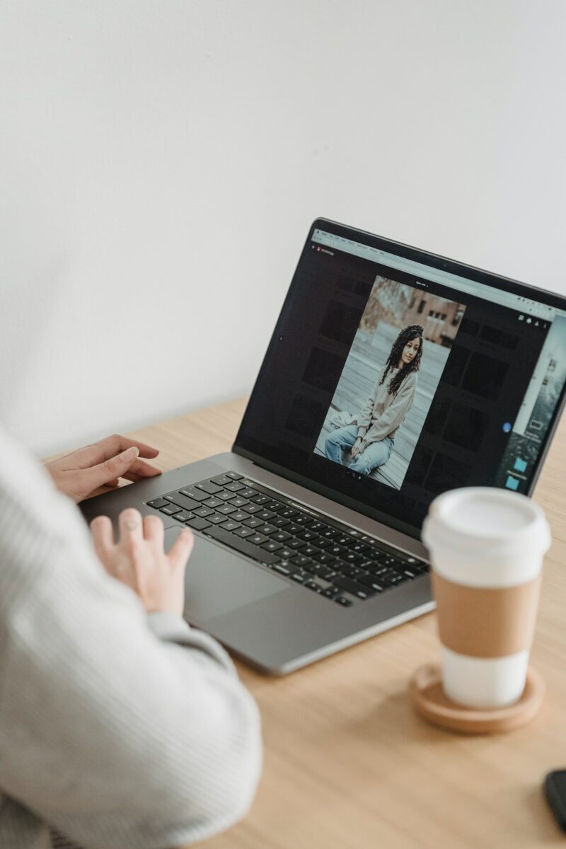 A person in long sleeves looking at the photos on the silver laptop