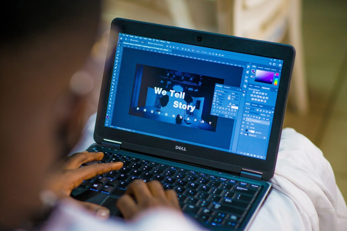 A person wearing a white shirt and white pants is using a black Dell laptop