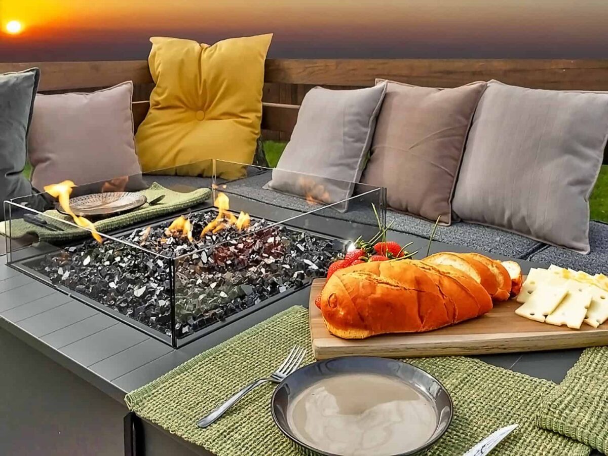 The image shows a cozy fireplace with a great sunset view