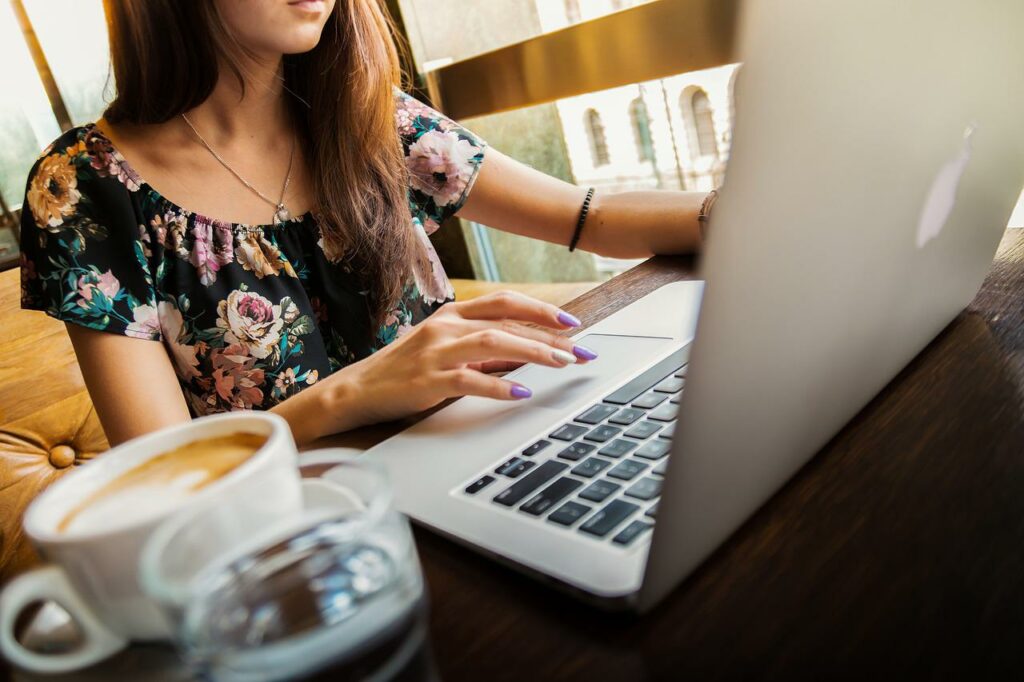 Una ragazza che usa il suo laptop mentre beve il caffè