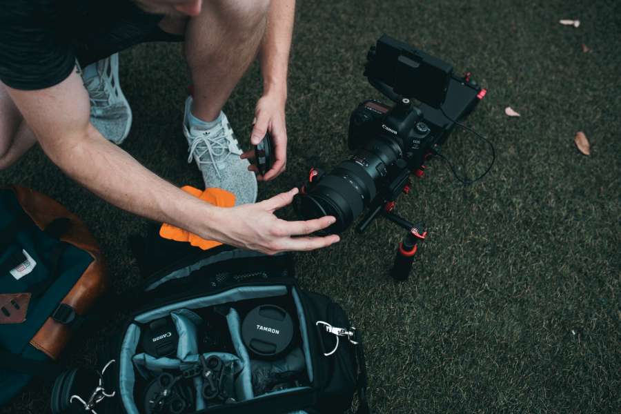 Uomo che mette la sua attrezzatura fotografica all'interno di una borsa fotografica