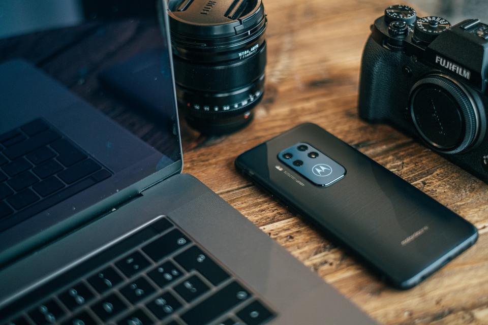 Camera and smartphone beside laptop