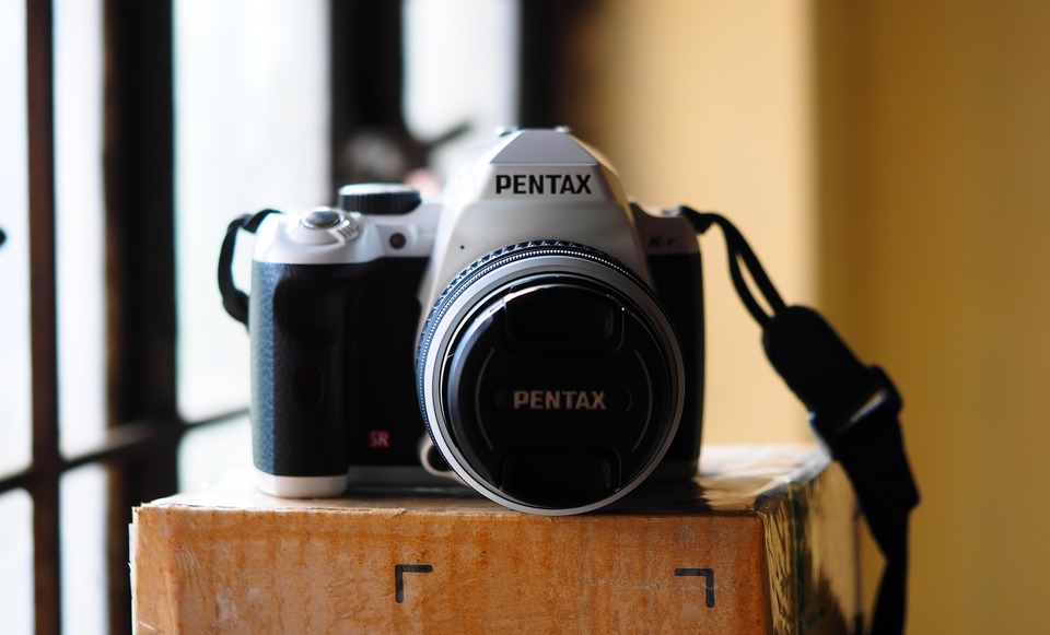 Fotocamera Pentax nera e argento posizionata su una scatola marrone