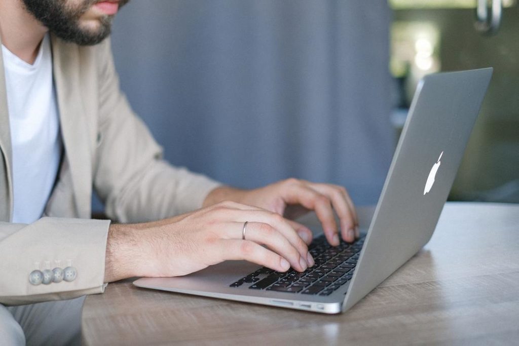 Uomo in vestito che scrive sul computer portatile