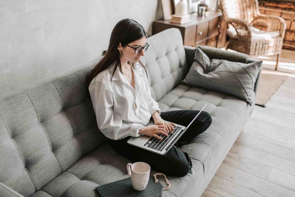 Femme utilisant un ordinateur portable assis sur un canapé