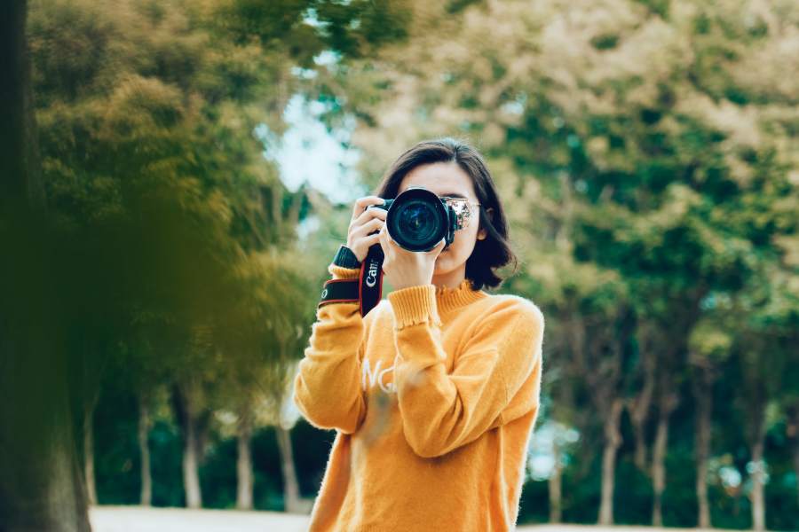 A girl wearing a yellow shirt taking a photo